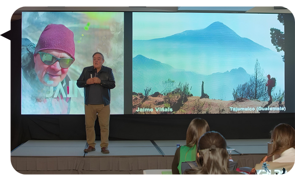 Jaime Viñals ofrece una conferencia frente a una pantalla con imágenes del volcán Tajumulco y una foto personal.